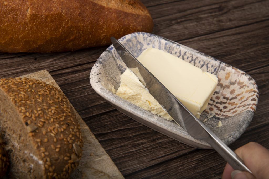 close up view kinfe cutting butter breads around wooden background - خليط الدهون النباتية غير مملحة للمخبوزات