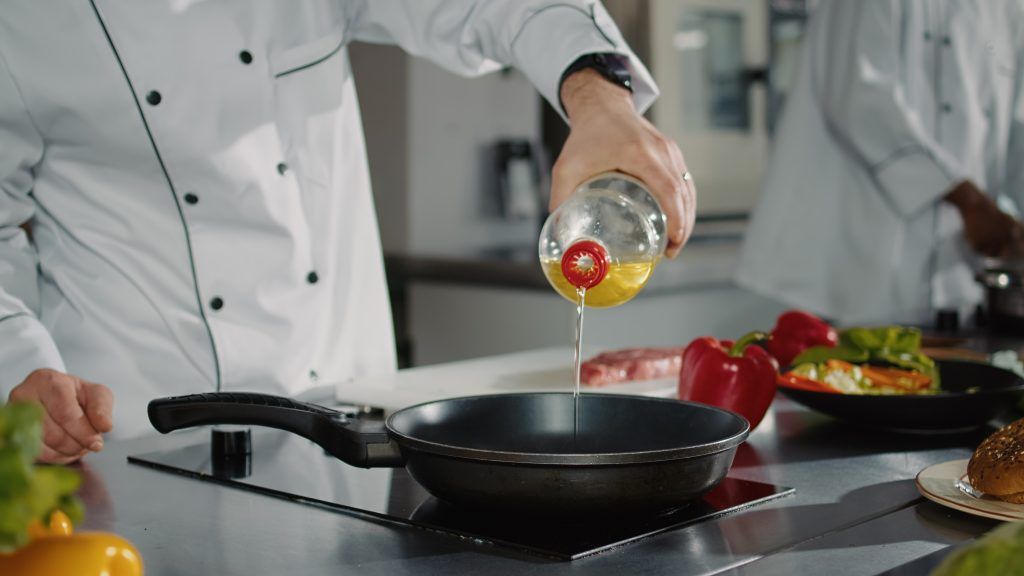 male chef pouring sunflower oil from bottle pan stove preparing frying liquid make delicious gourmet meal professional man cooking meat organic vegetable recipe close up - الطباخ السعيد أفضل زيت للطبخ والقلي من بيكرز تشويس